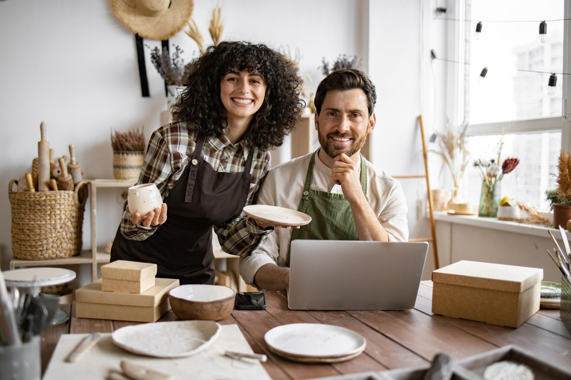 Un hombre maduro y una mujer joven de cabello rizado en delantales usan una computadora portátil para hacer el inventario