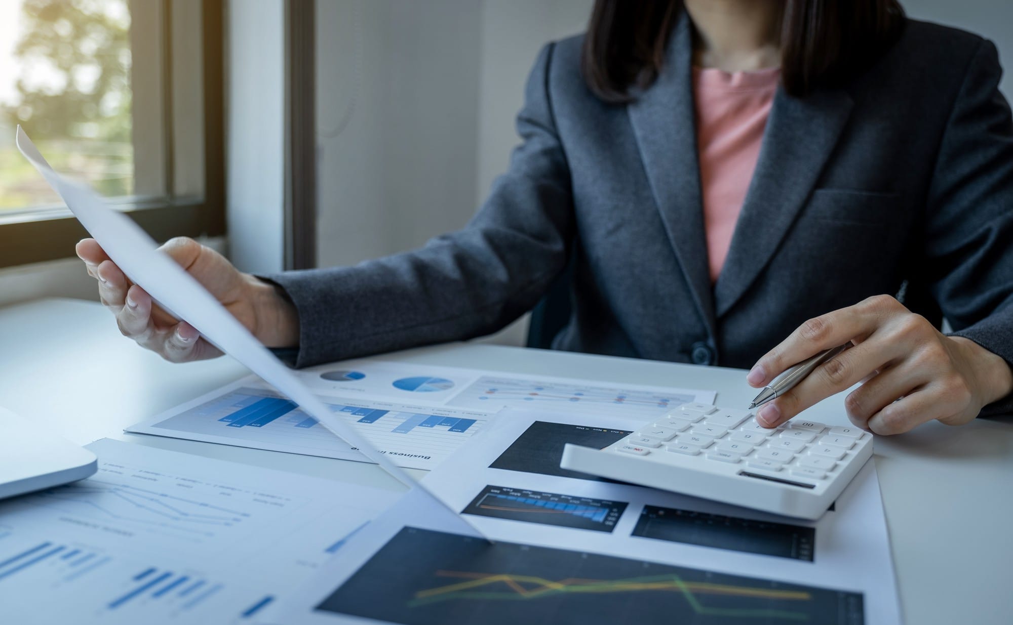 Calculadora de uso de mano de empresaria, gráfico de análisis en la oficina en casa para establecer objetivos comerciales